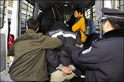 下火车后，嫌犯被押上警车。本报记者 董世彪 摄